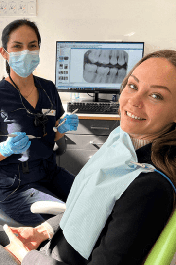A dentist in epsom works with a happy patient at Alpers Dental